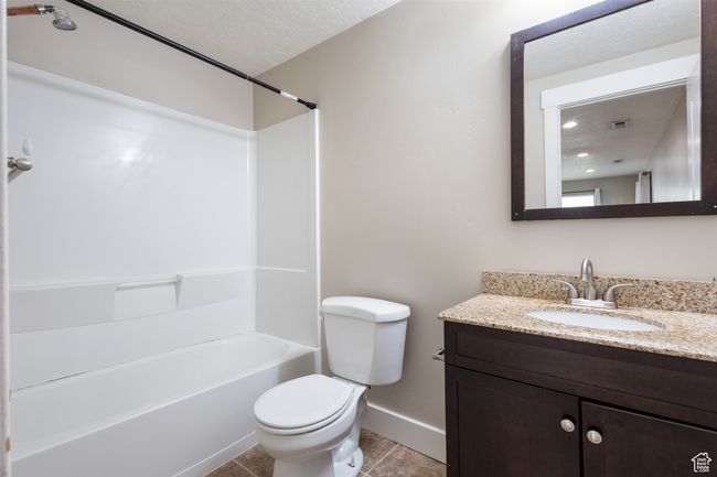 Bathroom with vanity, tile patterned flooring, shower / bath combination, and a textured ceiling | Image 28
