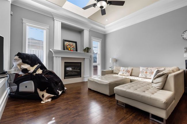 Living room with ornamental molding, ceiling fan, a glass covered fireplace, wood-type flooring, and recessed lighting | Image 15