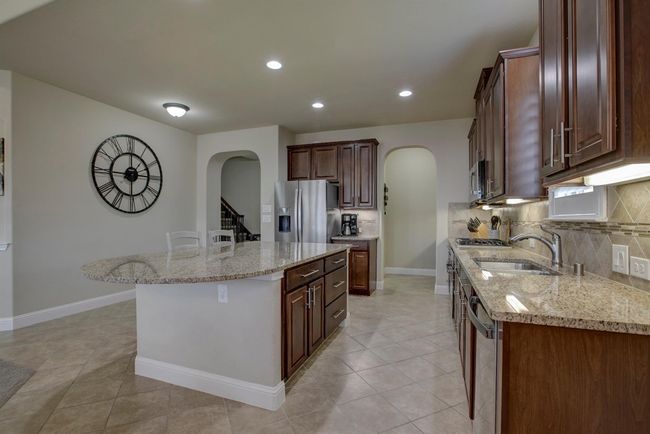 Kitchen featuring arched walkways, stainless steel appliances, decorative backsplash, a kitchen island, and recessed lighting | Image 6