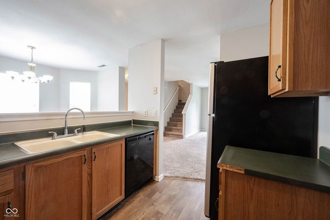 kitchen featuring dark countertops, dishwasher, brown cabinetry, a sink, and light wood-style flooring | Image 18