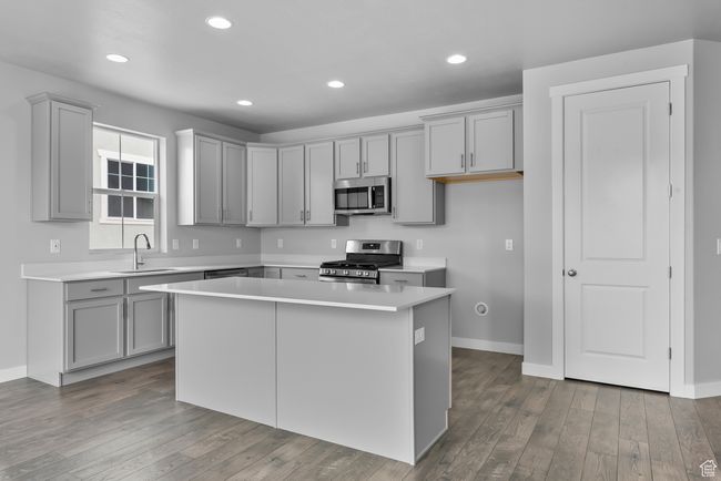 Kitchen with stainless steel appliances, gray cabinetry, a kitchen island, light countertops, and recessed lighting | Image 16
