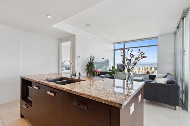Kitchen featuring a sink, dark brown cabinets, light tile patterned flooring, open floor plan, and a center island with sink | Image 5