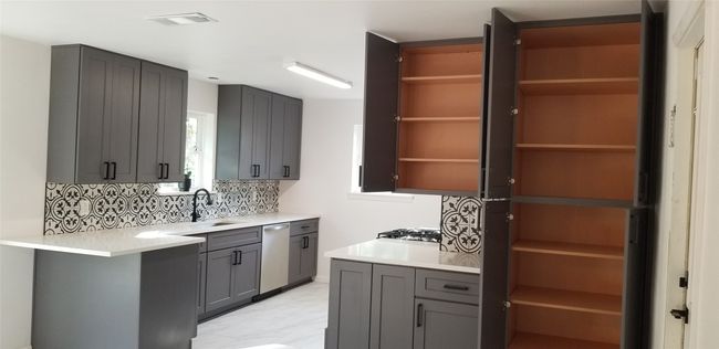 Kitchen featuring open shelves, a sink, dishwasher, tasteful backsplash, and light countertops | Image 13