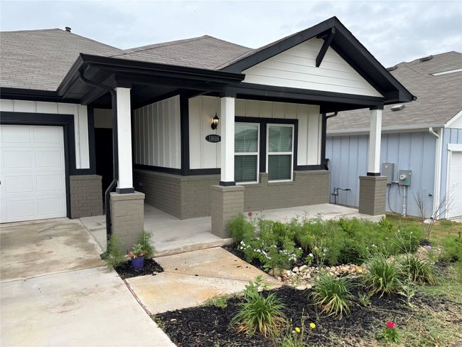 View of front of property featuring a porch, board and batten siding, brick siding, a garage, and a shingled roof | Image 4