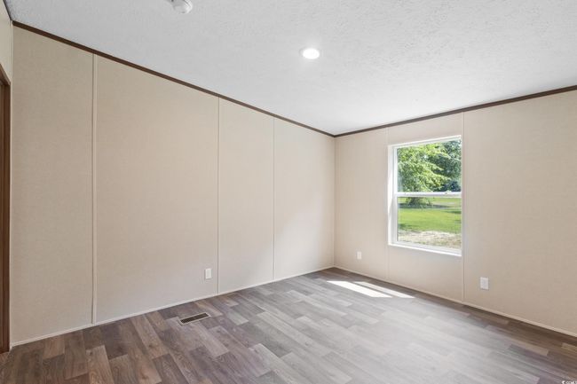 Empty room with wood finished floors, crown molding, a textured ceiling, and recessed lighting | Image 40