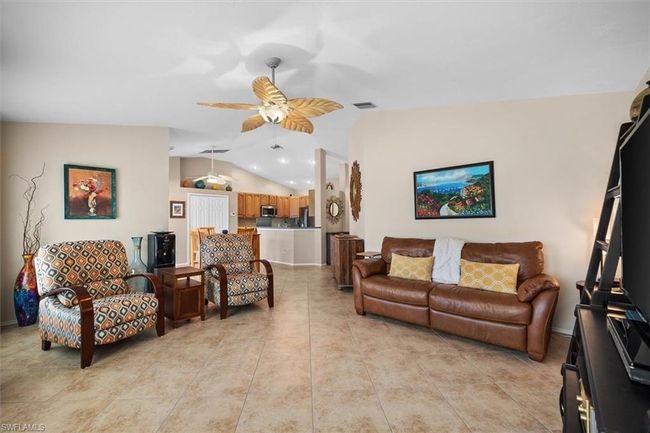 Living area with light tile patterned flooring, ceiling fan, vaulted ceiling, and visible vents | Image 20