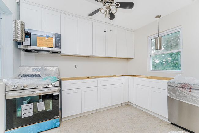 Kitchen featuring appliances with stainless steel finishes, ceiling fan, hanging light fixtures, and white cabinets | Image 18