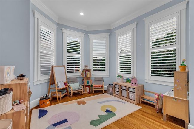 The breakfast room is currently being used as a bright and welcoming playroom with hardwood floors, large windows with shutters. | Image 18
