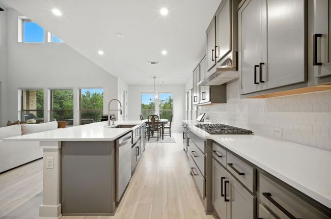 Kitchen with gray cabinets, light wood-type flooring, stainless steel appliances, backsplash, and recessed lighting | Image 13