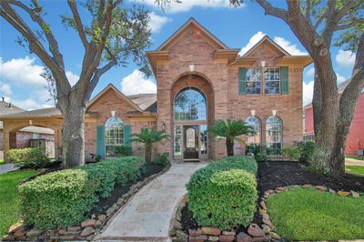 Welcome home to 5610 Lake Place Drive, a stately David Powers Traditional located in the exclusive gated community of Lakes on Eldridge. Lush landscaping flanks the stamped concrete walkway leading you to the grand two story entrance. | Image 1