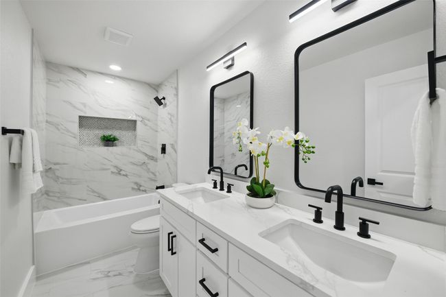 Full bathroom with double vanity, washtub / shower combination, toilet, marble look tiles, and recessed lighting | Image 34