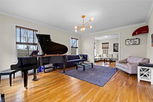 Living room with crown molding, light wood finished floors, and an inviting chandelier | Image 5