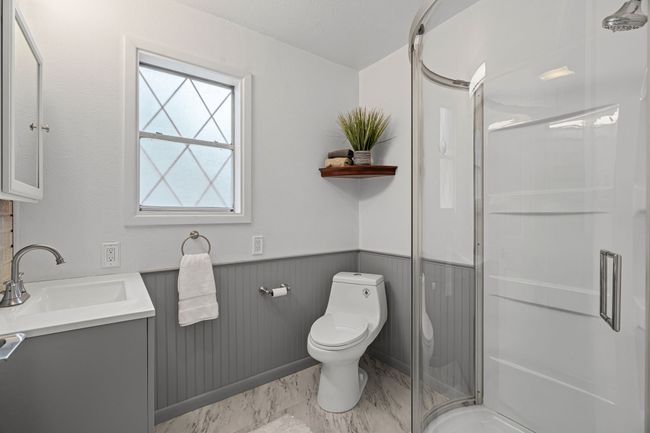Full bathroom featuring vanity, a stall shower, wainscoting, and marble look tile flooring | Image 19