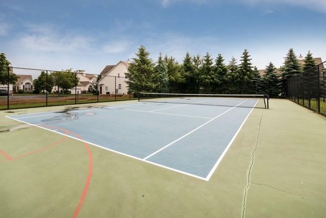View of tennis court featuring fence and a residential view | Image 42