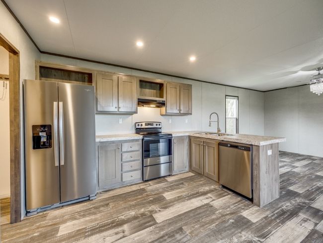 Kitchen with light countertops, light wood-style flooring, a peninsula, appliances with stainless steel finishes, and a sink | Image 8