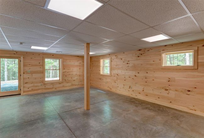 Unfurnished room featuring a drop ceiling, concrete floors, and wood walls | Image 35