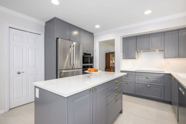 Kitchen featuring freestanding refrigerator, gray cabinetry, a center island, crown molding, and black electric cooktop | Image 11