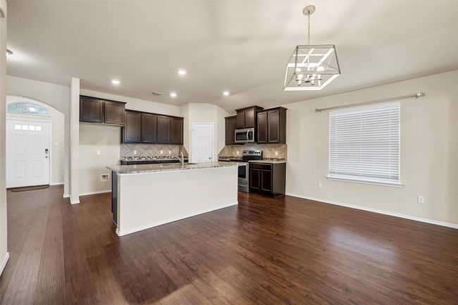 Kitchen with stainless steel appliances, dark brown cabinetry, tasteful backsplash, a kitchen island with sink, and recessed lighting | Image 15