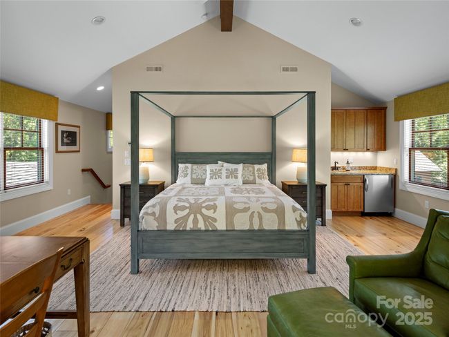 Stairs up from an enclosed hallway on the side of the garage lead you to the fourth ensuite bedroom above the garage. Coffee station in right corner includes granite countertop with sink, built-in beverage refrigerator and storage cabinets. | Image 36