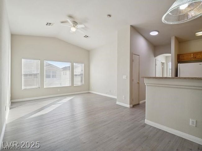 Unfurnished living room featuring light wood-style flooring, a ceiling fan, arched walkways, and lofted ceiling | Image 9