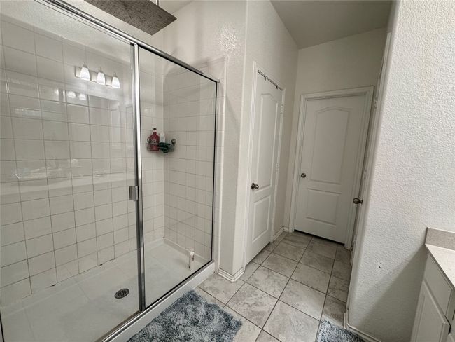 Full bathroom featuring a shower stall, a textured wall, and vanity | Image 20