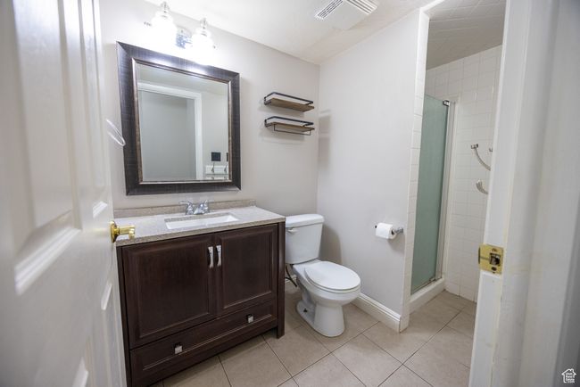 Bathroom with a shower stall, vanity, and tile patterned flooring | Image 8