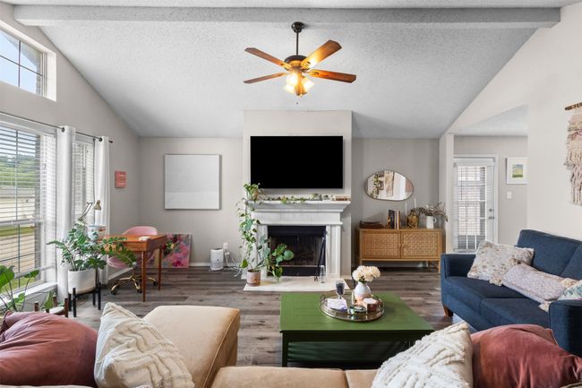 Living room featuring healthy amount of natural light, ceiling fan, wood finished floors, a fireplace with raised hearth, and high vaulted ceiling | Image 6