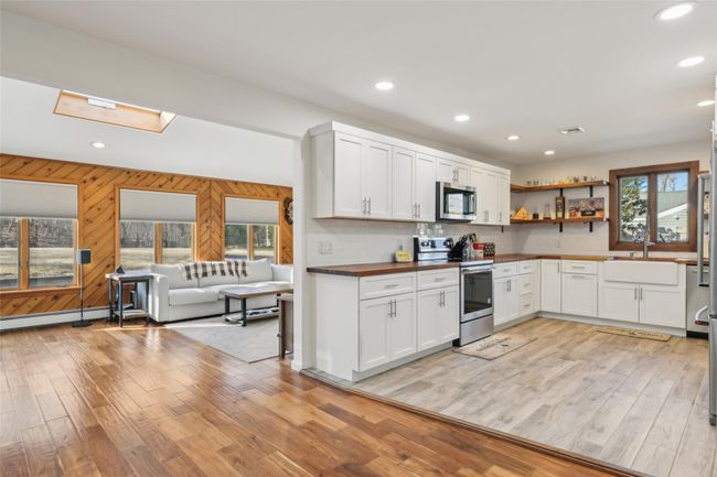 Kitchen featuring wooden walls, light wood finished floors, open shelves, stainless steel appliances, and open floor plan | Image 18