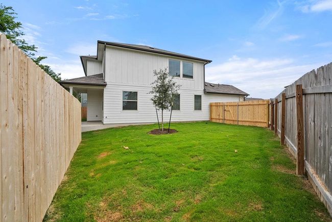 Rear view of house with board and batten siding, a fenced backyard, and a patio | Image 25