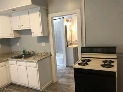 Kitchen featuring white cabinets, white gas stove, sink, and dark hardwood / wood-style flooring | Image 2