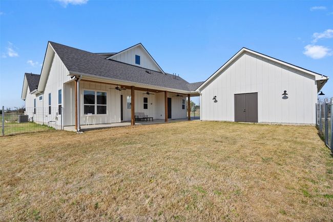 Rear view of house featuring a ceiling fan, cooling unit, board and batten siding, roof with shingles, and a patio area | Image 26