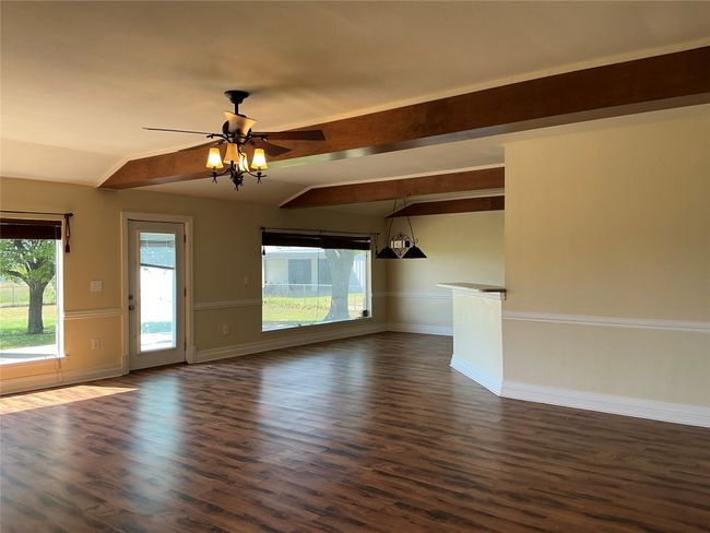 Unfurnished living room with baseboards, vaulted ceiling with beams, dark wood-style floors, and a ceiling fan | Image 5