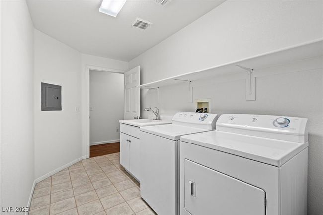 Walk-inside your private garage into the laundry room for added security. Additional highlights include a full indoor laundry room with custom cabinetry, countertop space, and a built-in sink for added convenience. | Image 25
