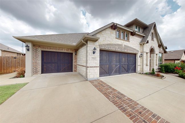 French country home with concrete driveway, stone siding, roof with shingles, and brick siding | Image 5