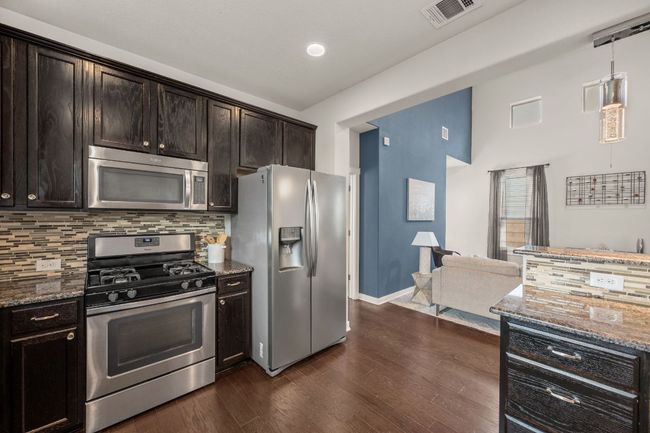Kitchen with stainless steel appliances, stone counters, tasteful backsplash, and dark wood-type flooring | Image 13