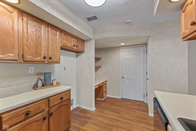kitchen with dishwasher, light countertops, light wood-type flooring, brown cabinets, and baseboards | Image 17
