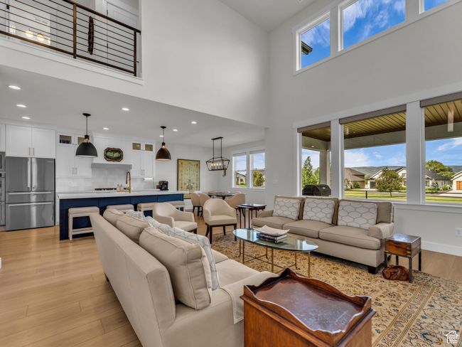 Living room with light wood finished floors, a towering ceiling, and recessed lighting | Image 11