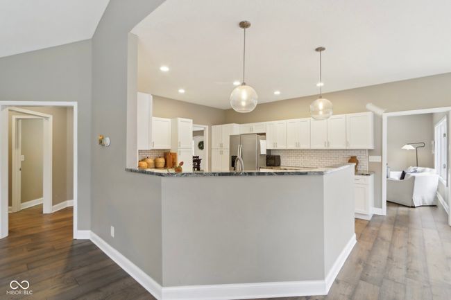 kitchen featuring dark stone counters, stainless steel fridge with ice dispenser, white cabinetry, and wood finished floors | Image 16