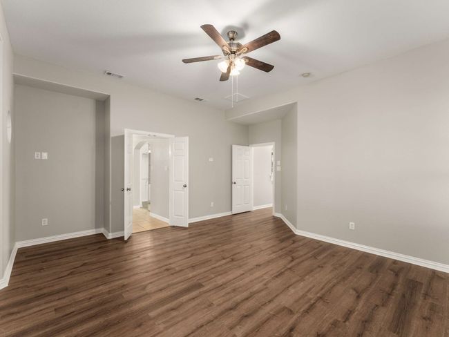 Unfurnished bedroom with a ceiling fan, wood finished floors, visible vents, and baseboards | Image 4