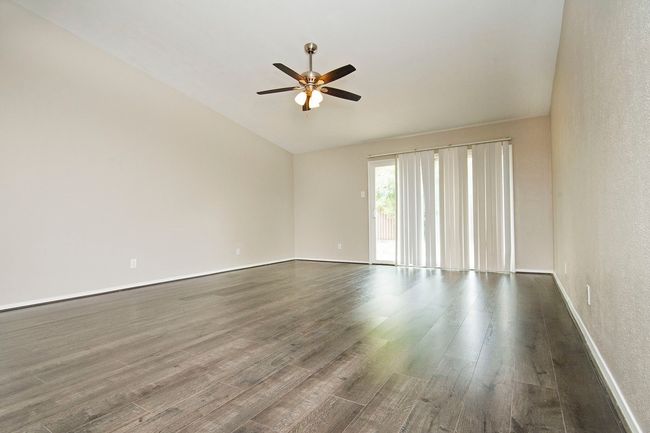 Unfurnished room featuring wood-type flooring, ceiling fan, and vaulted ceiling | Image 9
