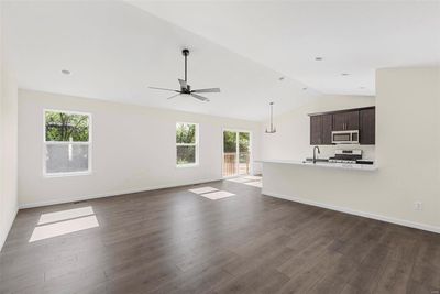 Unfurnished living room with lofted ceiling, ceiling fan, dark wood-type flooring, and a wealth of natural light | Image 3