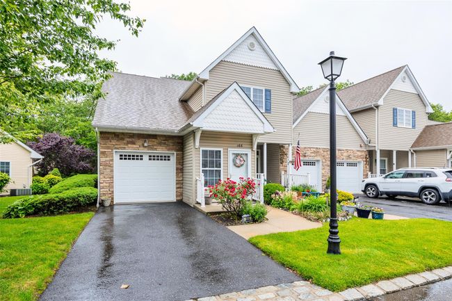 View of front of property featuring stone siding, a garage, a front lawn, and driveway | Image 29