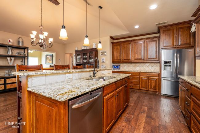 Kitchen with stainless steel appliances, a sink, lofted ceiling, dark wood-style floors, and a chandelier | Image 16
