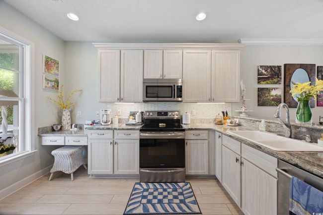 Kitchen featuring stainless steel appliances, decorative backsplash, recessed lighting, wood tiled floors, and light stone counters | Image 11