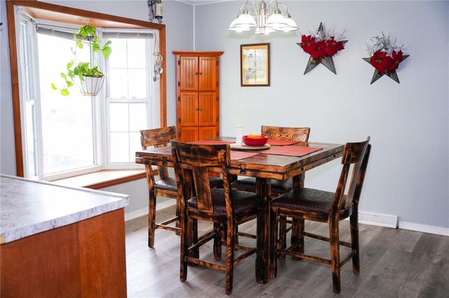 Dining area featuring a notable chandelier, baseboards, wood finished floors, and a healthy amount of sunlight | Image 5