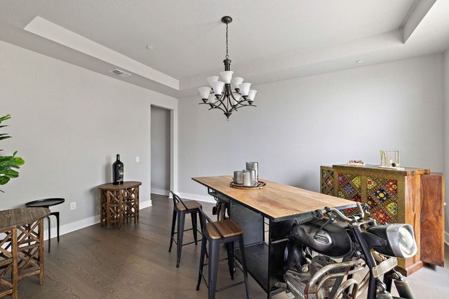 Dining room featuring visible vents, baseboards, a chandelier, a tray ceiling, and wood finished floors | Image 22