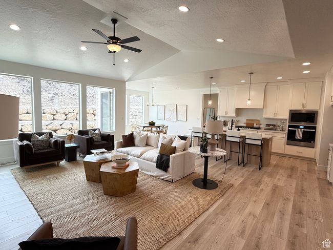 Living area with lofted ceiling, light wood finished floors, a textured ceiling, and recessed lighting | Image 5