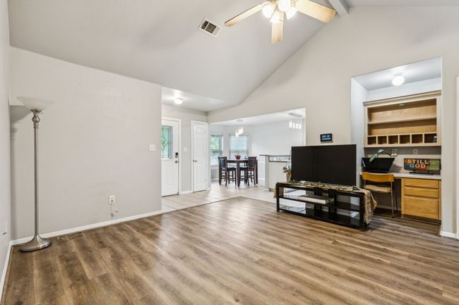 Living room with wood finished floors, ceiling fan, beam ceiling, built in desk, and high vaulted ceiling | Image 12