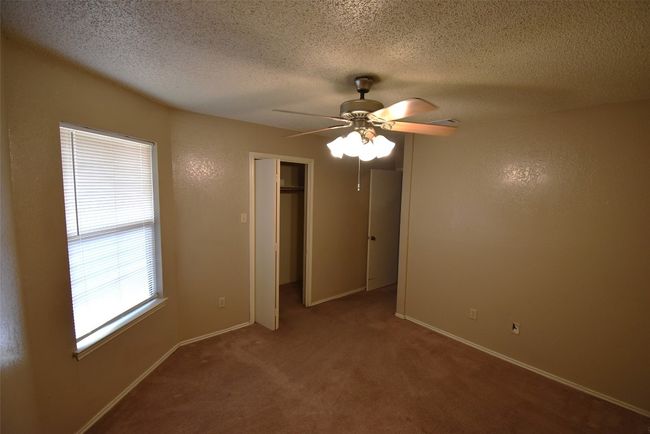 Unfurnished bedroom with a textured ceiling, carpet flooring, a closet, and a ceiling fan | Image 8