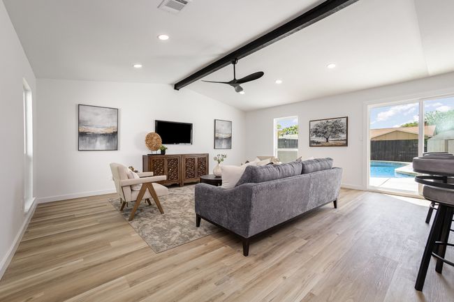 Living area with baseboards, lofted ceiling with beams, visible vents, ceiling fan, and light wood finished floors | Image 13